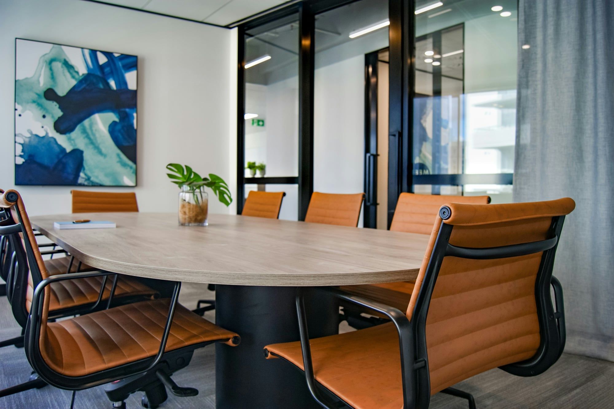 A meeting room with a wooden table and tan leather chairs in a quiet office
